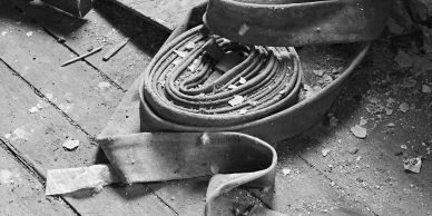 Old coiled fire hose on dusty floor.