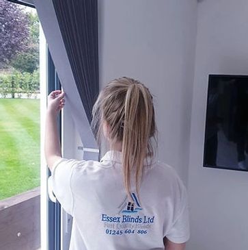 A person adjusting a window blind in a modern room.