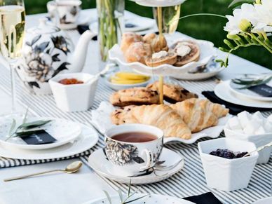 Elegant tea setup with croissants and pastries on a striped tablecloth.