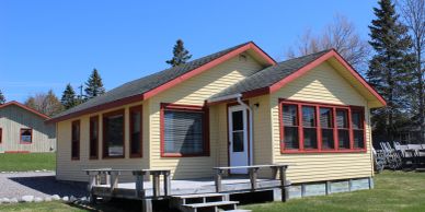 A small yellow house with red trim under a clear blue sky.
