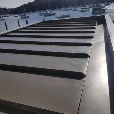 Large piano key sculpture by the waterfront with boats.