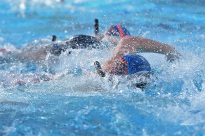 Athletes swimming fiercely in a competitive race in a pool.