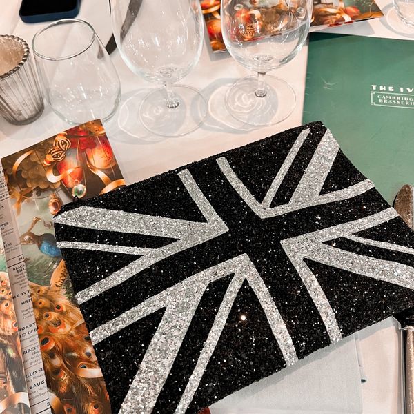 Black and silver Union Jack flag glitter clutch bag on a dining table. 