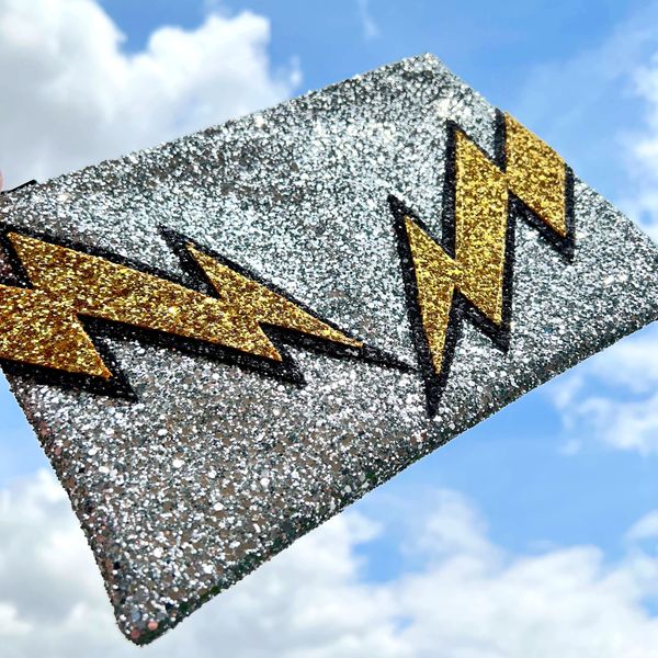 Lightening bolt glitter clutch bag held up to the sky. 