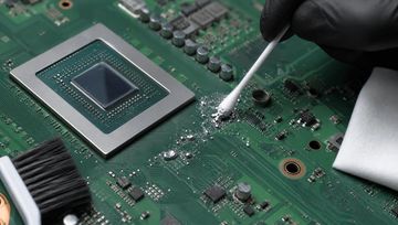 Shows a PCB with someone cleaning up liquid metal.