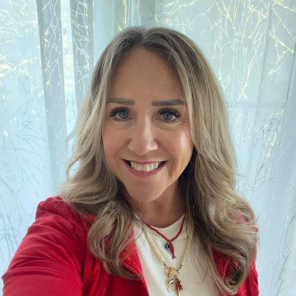 Smiling woman with wavy blonde hair in a red jacket.