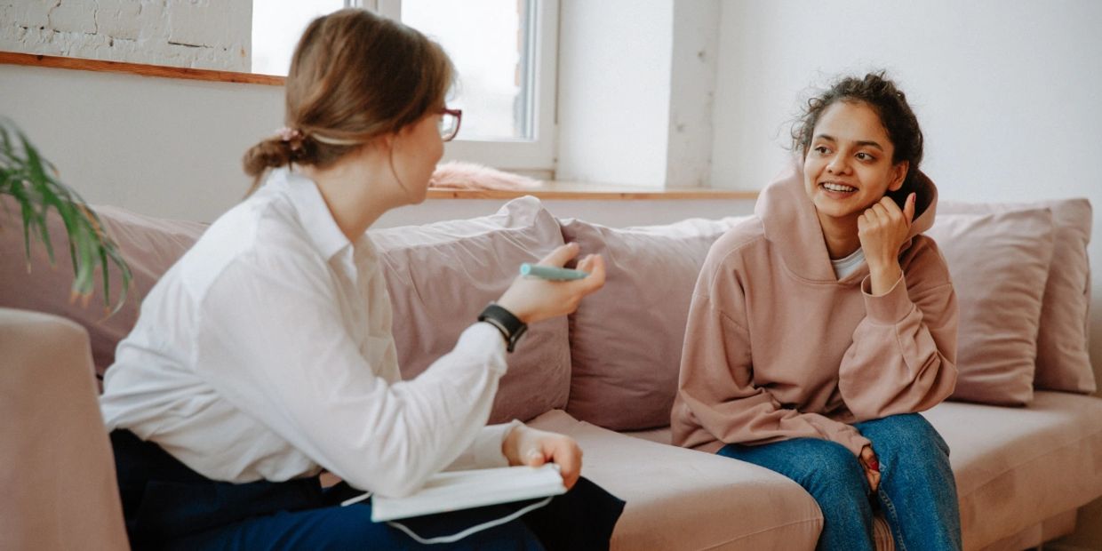 Two women having a friendly conversation on a couch.