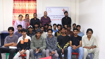 Group photo of young men and women in a classroom setting.