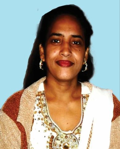 Smiling woman wearing traditional attire with earrings against a blue background.