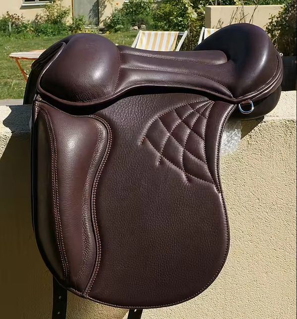 Close-up of a brown leather horse saddle with detailed stitching.