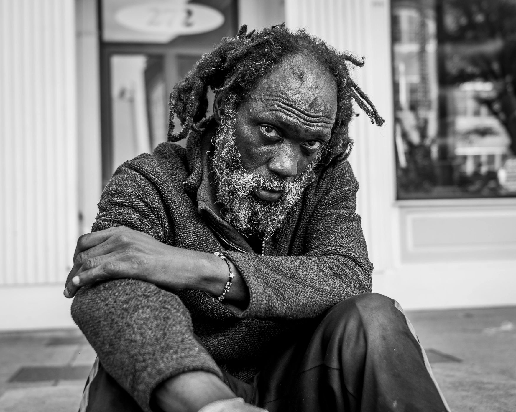 Black and white portrait of a contemplative man with dreadlocks.