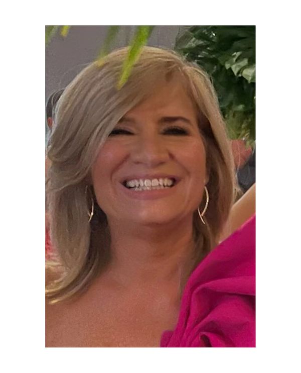 Smiling woman with blonde hair and hoop earrings.