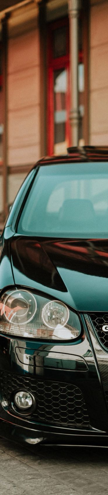 Close-up of a sleek black car front with shiny headlights and grille.