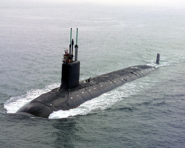 A large black submarine cruising on the ocean surface with its conning tower raised.