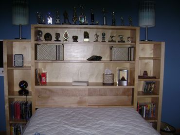 Custom maple bookcase headboard with sliding lower panels for hidden storage.  