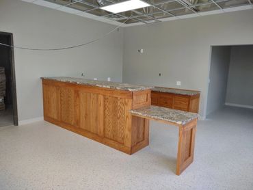 Oak front office cabinets and shelves. ADA accessible desk. Laminate countertop. Locking cash drawer