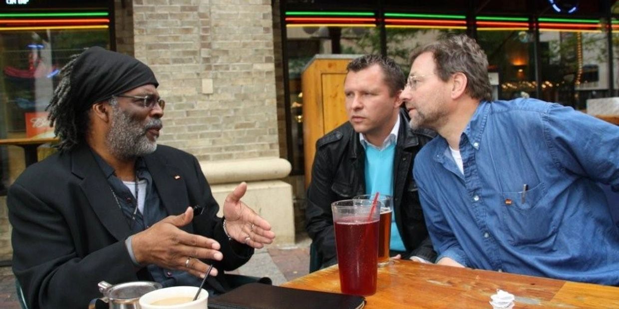 Three men engaged in a deep conversation at an outdoor cafe.