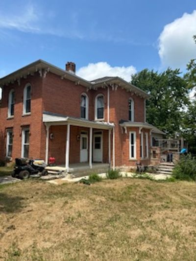 Two-story brick house with a covered porch and lawn.