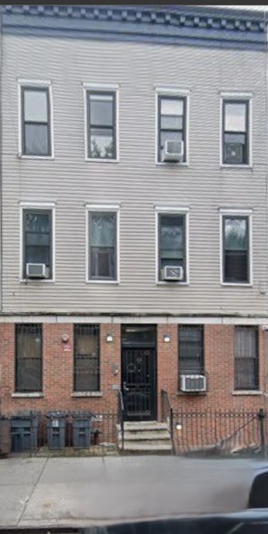 Three-story residential building with air conditioning units in windows.