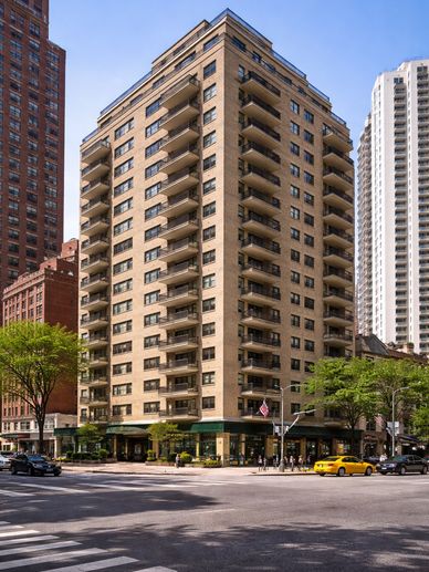 Corner view of a beige apartment building with balconies on a sunny day.