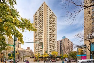 Tall residential building with balconies in an urban setting on a clear day.