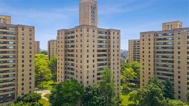 A cluster of tall residential buildings surrounded by greenery under a clear blue sky.