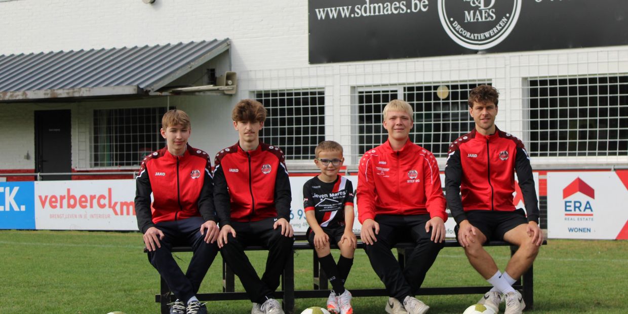 Voetbalteam zit op een bank op het veld.