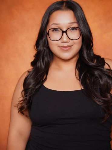 Woman with glasses and long black hair smiles.