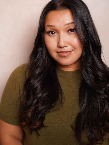 Smiling woman with long dark hair and green top.