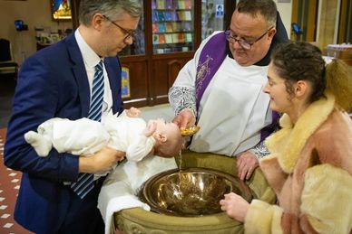 Baby being christened in church in Chesterfield. Father and mother and vicar. Baby baptism.