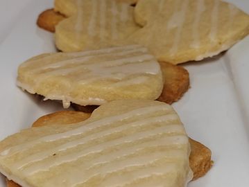 Lemon shortbread cookie heart shaped with frosting stripes.