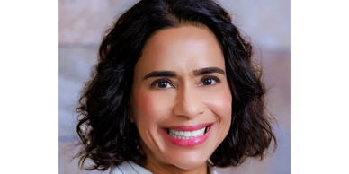 Smiling woman with curly dark hair and bright lipstick.