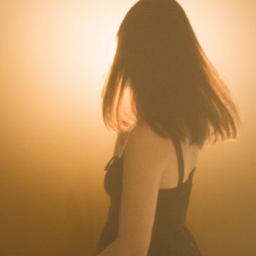 Silhouette of a woman with flowing hair against warm light.