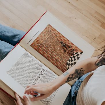 Person reading a book with an illustration of a brick room and a checkered floor.
