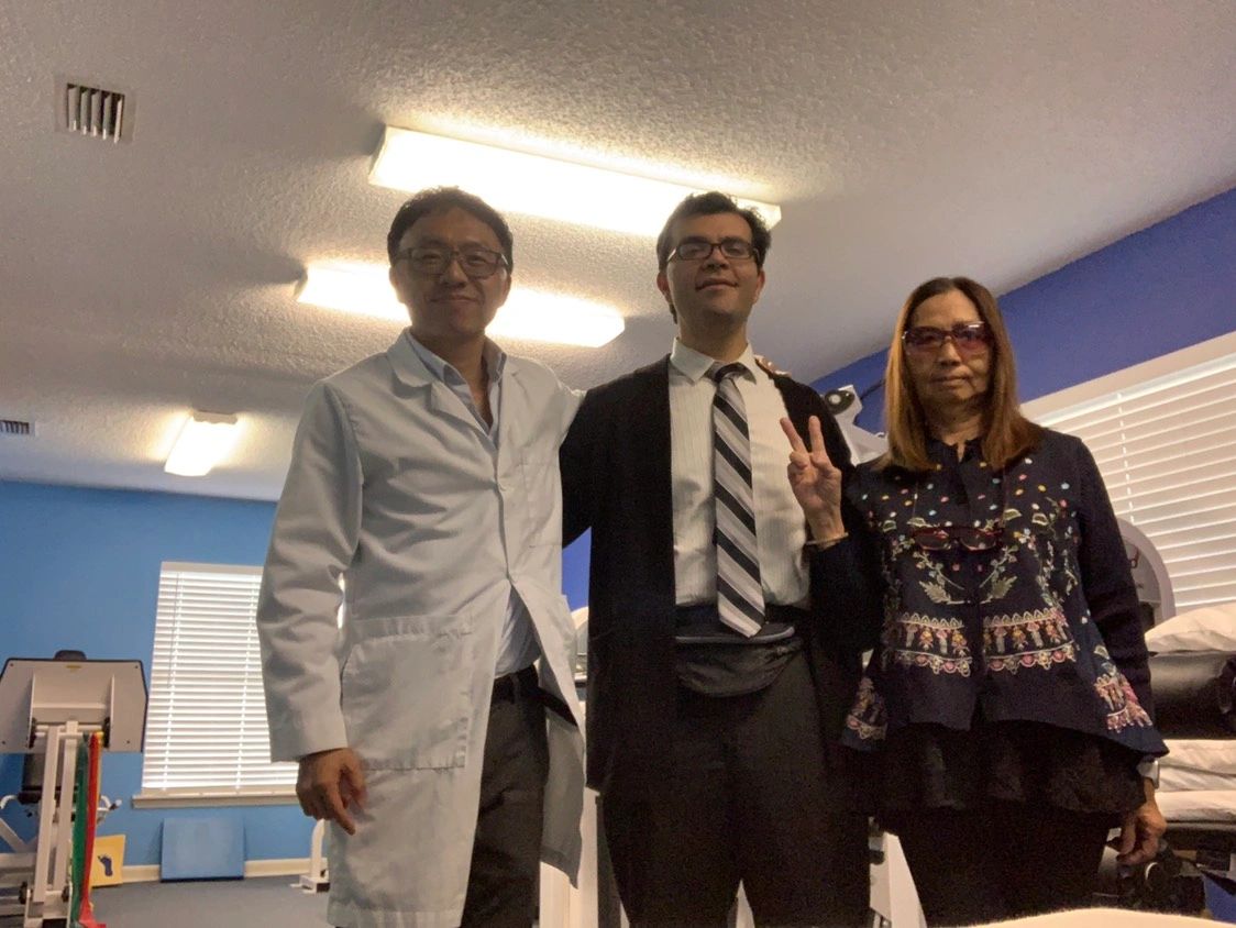 Three people posing in a well-lit room, one wearing a lab coat.