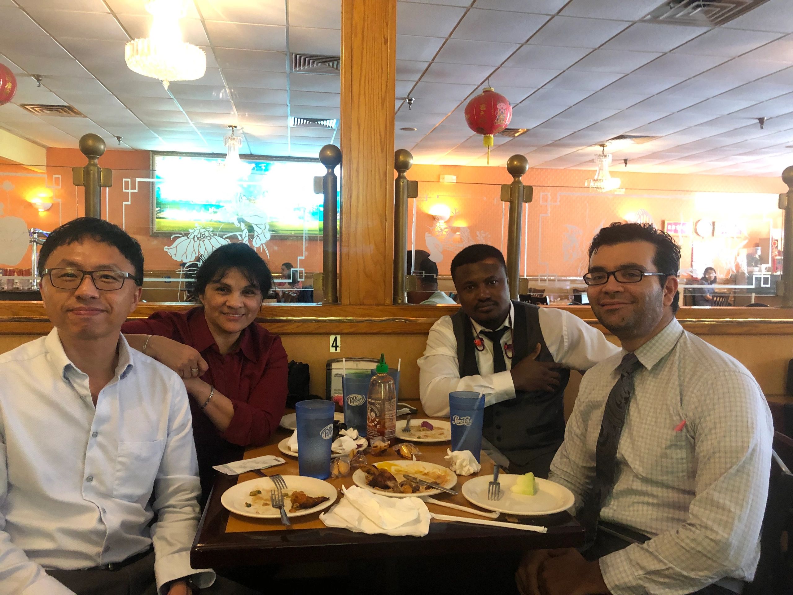 Four people sitting at a restaurant table with finished plates, smiling at the camera.