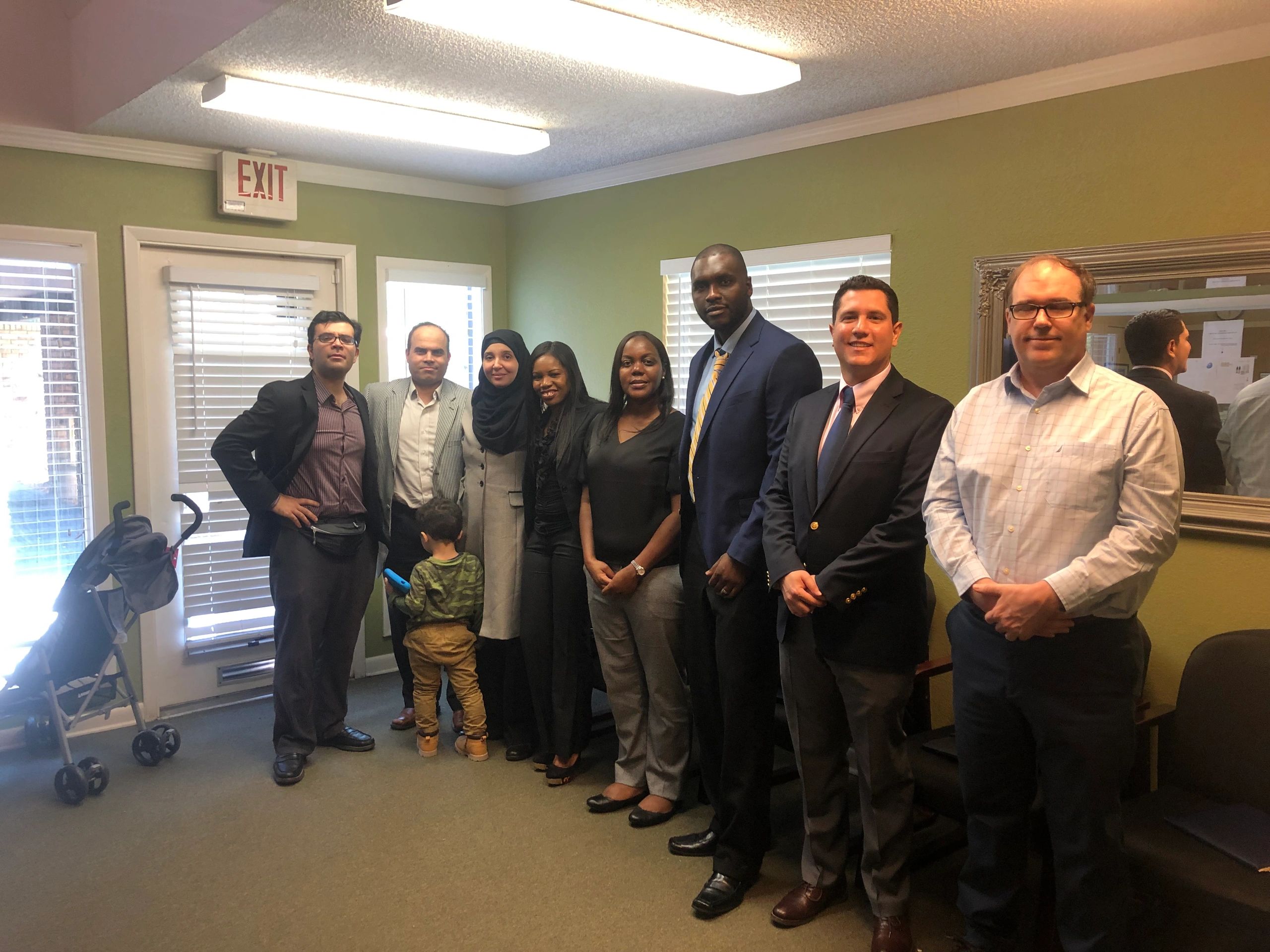 Group of professionally dressed people standing indoors for a photo.