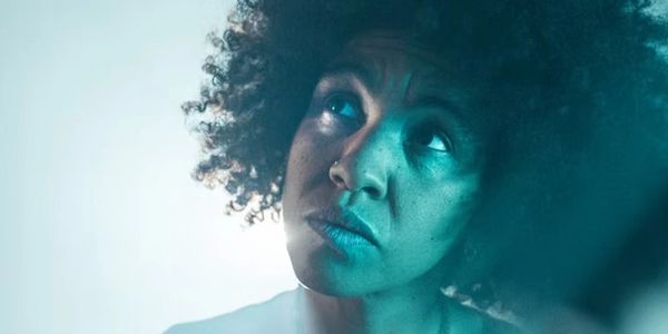 Portrait of a woman with curly hair looking thoughtfully upward.