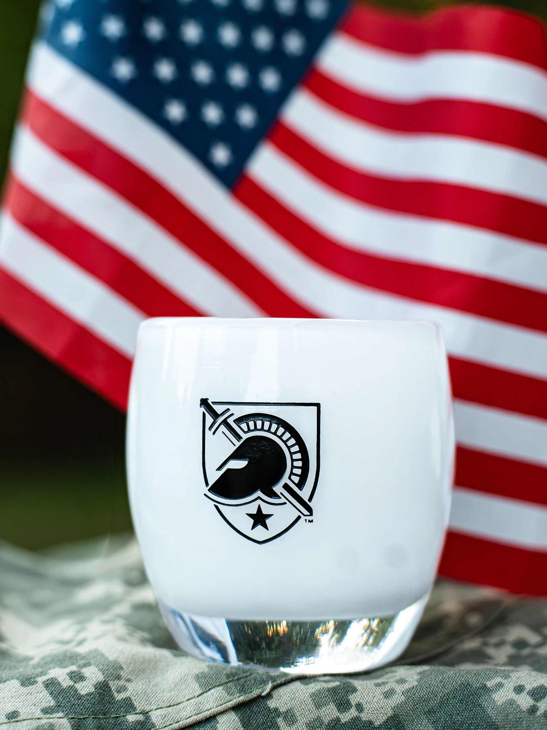 White glass with a warrior helmet logo and U.S. flag in background.