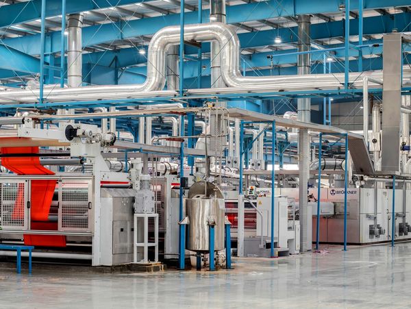 Interior of a modern industrial factory with machinery and ventilation pipes.