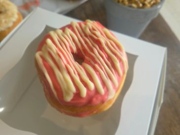 Donut with pink glaze and white drizzle icing.
