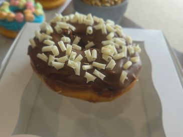 Chocolate donut with white chocolate shavings.
