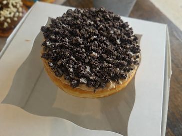 A donut topped with crushed chocolate cookies.