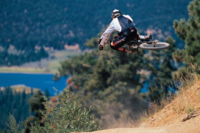 Mountain biker performing an airborne jump on a dirt trail.