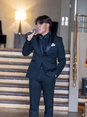 Two men in tuxedos performing on stage in an elegant setting.