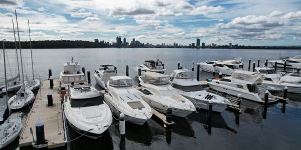 Luxury yachts docked at marina with Perth city skyline.