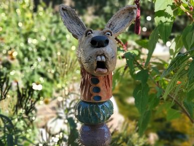 A whimsical ceramic rabbit sculpture in a garden.