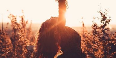 Woman enjoying a golden sunset in a field.