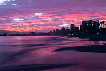 Stunning Long Beach sunset painting the rising tide with a surreal purple are pink