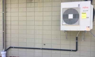Fujitsu multi-zone ductless mini split heat pump with mounting bracket on block wall